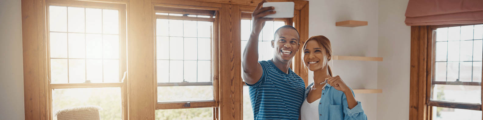 Couple taking a selfie in their new home while holding keys