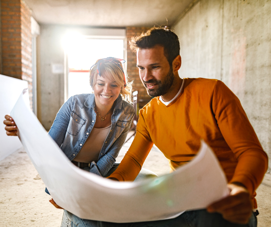 happy-couple-analyzing-plans-of-their-renovating-home Young couple examining blueprints during home renovation process.